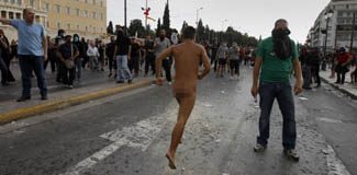 A naked protester runs through Syntagma Square by the parliament in Athens during a violent protest against the visit of Germany's Chancellor Angela