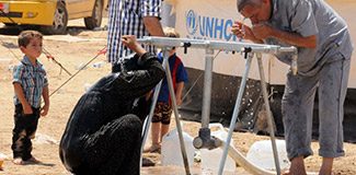 Mülteci kadınlar elbiseleriyle banyo yapıyor