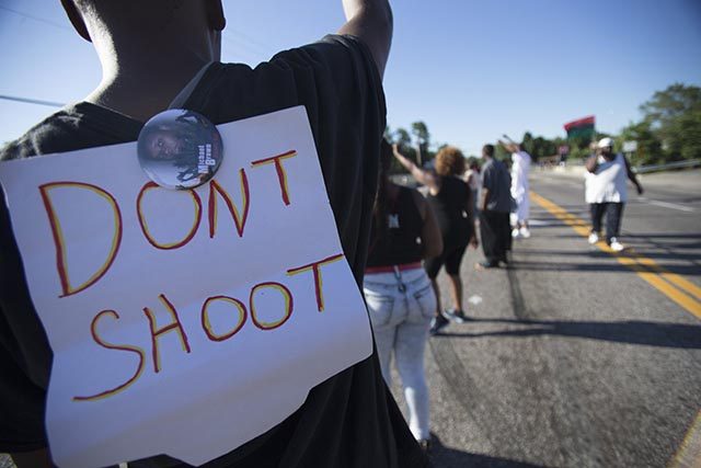 A sign and a pin are pictured on the back of a demonstrator during a protest against the shooting death of teenager Michael Brown, in Ferguson, Missouri