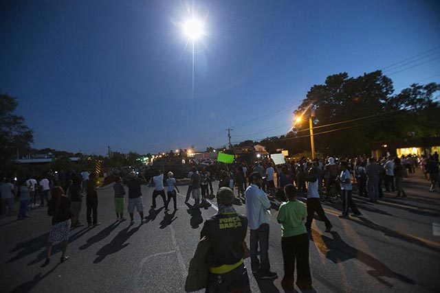 A police helicopter shines its light on demonstrators protesting the shooting death of teenager Michael Brown, in Ferguson, Missouri