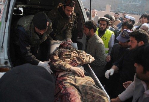 Policemen and civilians move a soldier, who was injured during an attack by Taliban gunmen on the Army Public School, outside a hospital in Peshawar