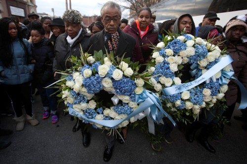 Civil rights activist Reverend Sharpton carries a wreath, flanked by Eric Garner's mother Gwen and widow Esaw during Martin Luther King Day activities in the Brooklyn borough of New York