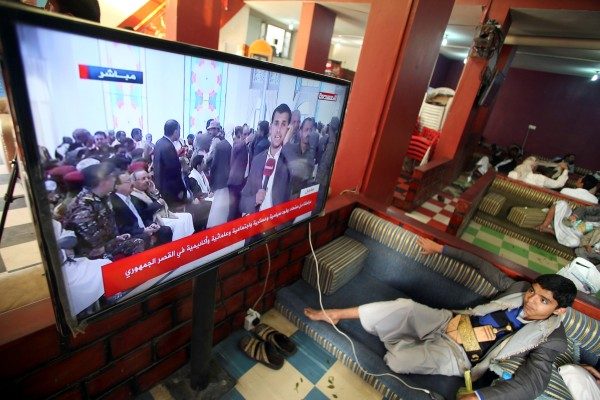 A boy watches television as an announcement by the Houthi movement on dissolving the parliament is made in Sanaa