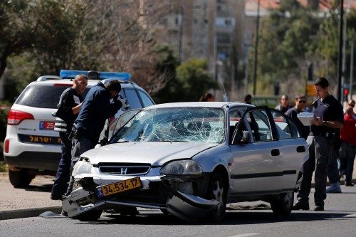 Israeli policemen inspect the car used by a Palestinian motorist to ram into a group of pedestrians in Jerusalem