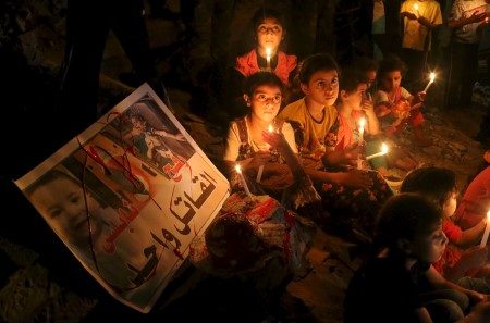 Palestinian children light candles during a rally to remember 18-month-old Palestinian baby Ali Dawabsheh who was killed after his family's house was set on fire in a suspected attack by Jewish extremists in Rafah in the southern Gaza Strip
