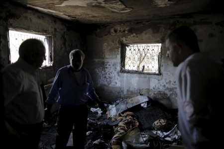 Palestinians inspect a house which was set on fire in a suspected attack by Jewish extremists in Duma village near Nablus