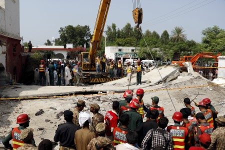 Rescue workers use a crane to lift sections of the collapsed roof after a blast near the home of the home minister of Punjab province, Shuja Khanzada, in Attock