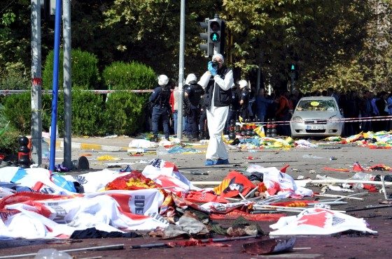 A police forensic expert takes pictures as he examines the scene following explosions during a peace march in Ankara, Turkey