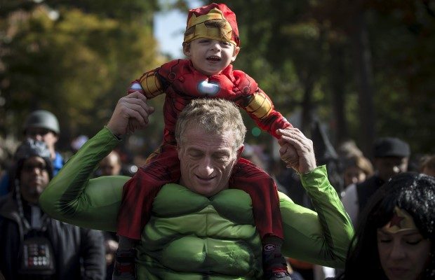 Child dressed as Ironman rides on an adult's shoulders who is dressed up as the Hulk as they take part in the Children's Halloween day parade at Washington Square Park in the Manhattan borough of New York