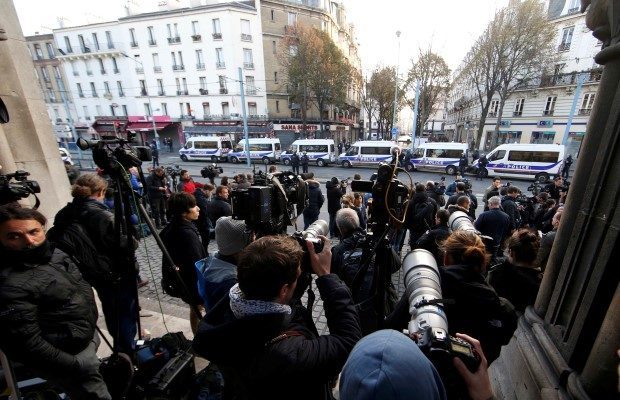 Journalists gather at the scene near police vans in Saint-Denis, near Paris
