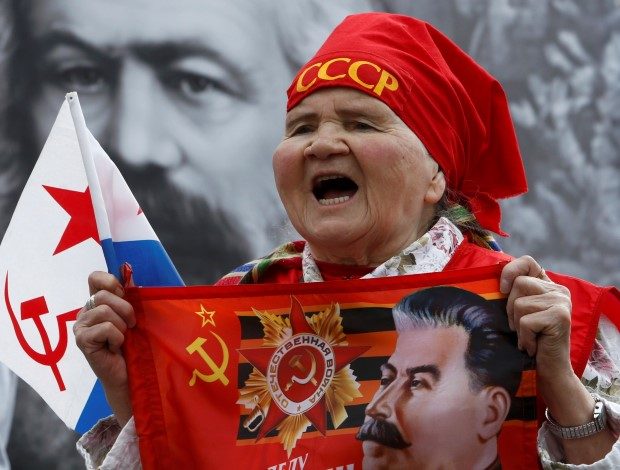 A supporter of the Communist party shouts slogans during a May Day rally, with a portrait of co-author of 