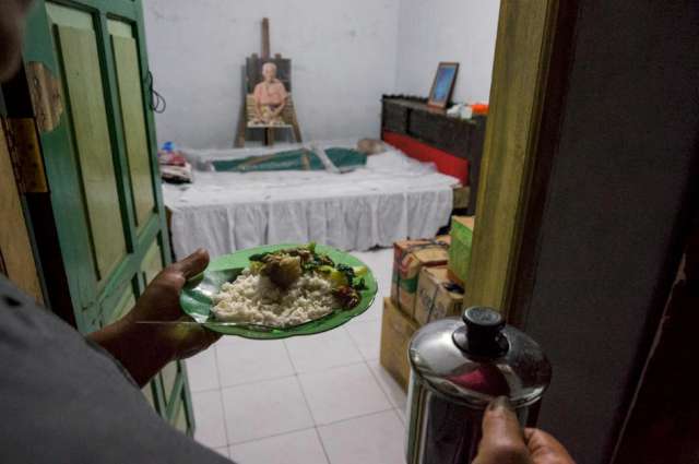 Fotoğraf: National Geographic Risma Paemboan, iki hafta önce 84 yaşında ölen eşinin annesinin cansız bedenine yemek götürüyor.