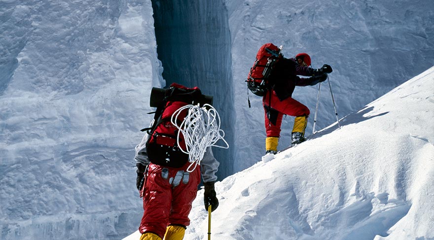 Doğal bir buz köprüsünü aşan dağcılar