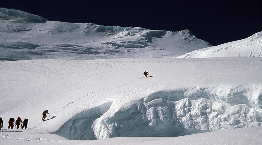 Buzul çatlağı riskine karşı dağcılar birbirine bağlı halde emniyet alarak ilerliyor. 