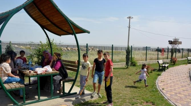 Sınırda asker eli tetikte görev yapıyor, çocuklar ise parkta oynuyor