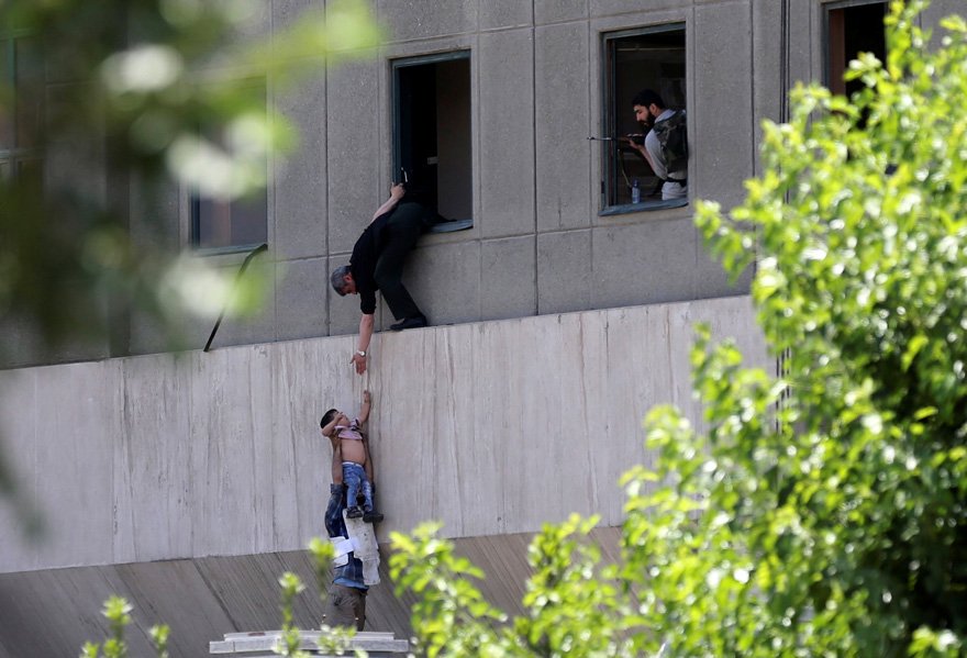 FOTO: REUTERS/ İran Meclisi'nde baskın sürerken bir çocuk binadan böyle çıkarıldı.