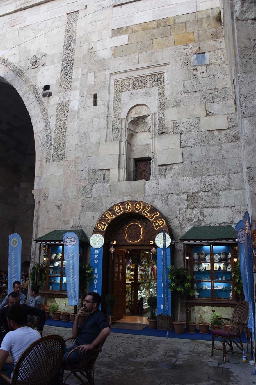 Hediyelik eşya satan dükkanın kapı ve pencereleri Çifte Minareli Medrese’nin duvarında...