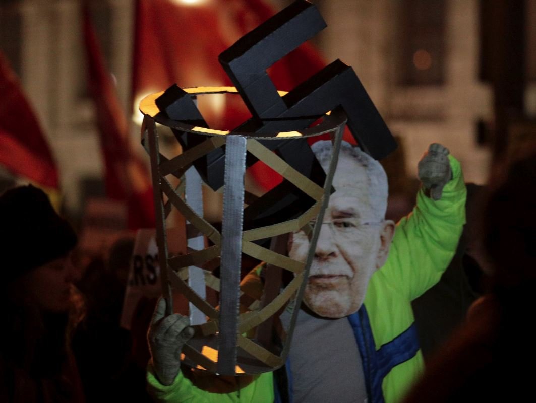 Gamalı haç taşıyan bir gösterici, Avusturya Cumhurbaşkanı Alexander Van der Bellen maskesi taktı.